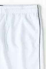 Short de fútbol blanco en malla, modelo de corte relajado con cintura elástica ajustable mediante cordón, bolsillos laterales y líneas negras decorativas en los laterales. Cuenta con el logo de Lotto estampado en contraste en una pierna.