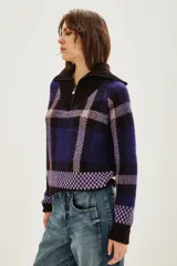 Cardigan de punto con diseño de cuadros en tonos azul, violeta y negro. Presenta cuello alto con cierre frontal y mangas largas.