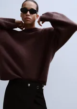 Jersey de punto color marrón oscuro, con cuello redondo y diseño oversize de manga larga.