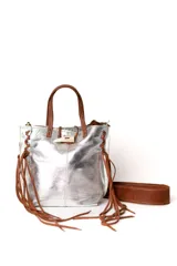 Mini cartera de cuero plateado con detalles en cuero marrón. Presenta flecos laterales largos, manijas superiores y un cierre frontal tipo cuerno. Incluye una correa larga ajustable y extraíble.