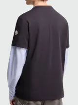 Remera de manga corta color negro con bordado Moncler Archive en el pecho, diseñada con un efecto de capas que incluye mangas largas de camisa en color celeste y cuello en tono marrón.