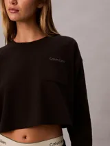 Top cropped de manga larga Calvin Klein, confeccionado en punto de algodón. Presenta cuello redondo, hombros caídos y un bolsillo de parche en el pecho con el logo de la marca bordado.