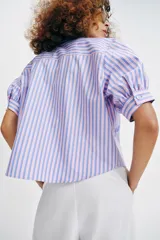 Camisa de cuello solapa y mangas cortas abullonadas, con diseño de rayas verticales en tonos rosados y celestes, decorada con lentejuelas bordadas.