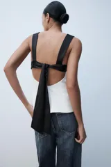 Top de escote cuadrado y tirantes anchos, con diseño bicolor en negro en la parte superior y blanco en el cuerpo, corte ligeramente acampanado y espalda descubierta con lazada.