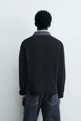 Polo de punto color azul marino, de calce relajado y manga larga. Presenta un cuello solapa de tejido denim en contraste con una abertura frontal en forma de V.