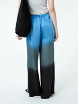 Pantalón palazzo celeste con degradé a gris y negro, de tiro alto con cintura elastizada y cordón ajustable.