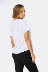 Blusa blanca con estampado floral negro, de corte recto y manga corta.