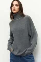 Polera gris de tejido de punto, corte oversized, cuello alto y mangas largas.