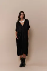 Vestido negro de corte midi, con escote en V y mangas cortas amplias. Presenta un cuello blanco con volados.