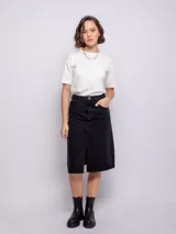 Falda midi de jean color negro, con diseño de cinco bolsillos, cierre frontal con botón metálico y abertura central en el bajo.