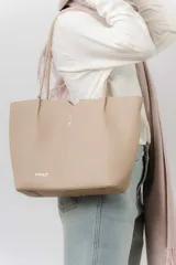 Cartera tipo tote de diseño amplio y estructurado, confeccionada en material sintético con textura graneada. Cuenta con doble asa larga para llevar al hombro y logo de la marca aplicado en el frente.