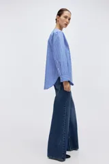 Camisa de algodón con diseño a rayas azules y blancas, corte oversized, escote en V profundo y mangas largas con hombros caídos y puños anchos.