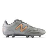 Championes de fútbol New Balance 442 V2 Team FG, color gris con detalles en cobre. Confeccionados en cuero, con tapones de TPU para terrenos firmes y forro interno confortable.