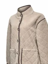 Chaqueta de polar color beige con diseño acolchado de rombos y ribetes en contraste. Presenta cierre frontal de botones, cuello alto, manga larga y bolsillos delanteros aplicados. Confeccionada en poliéster reciclado con detalles de cuero.