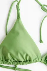 Top de bikini triangular de color verde con relleno extraíble, tiras finas ajustables para el cuello y la espalda, y detalle de nudos decorativos en los breteles.