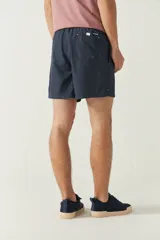 Short de baño liso para hombre, con cintura elástica y cordón ajustable. Cuenta con dos bolsillos laterales, un bolsillo trasero y logo bordado en la parte inferior.