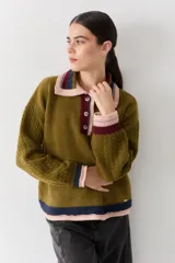 Buzo de lana tipo polo con cuello y cartera de botones en colores contrastantes. Presenta mangas con textura de ochos y puños y ruedo con terminaciones en franjas de colores.