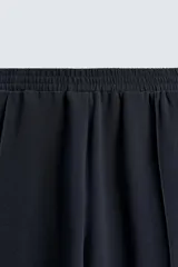 Pantalón relaxed fit color azul marino, confeccionado en tejido fluido con viscosa. Cuenta con cintura elástica ajustable con cordón interior, bolsillos laterales y bolsillos traseros de vivo. Las perneras tienen costura frontal y el bajo es ajustable con cremalleras laterales.