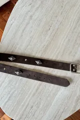 Cinturón de cuero vacuno color chocolate con apliques metálicos en forma de diamante y hebilla plateada.