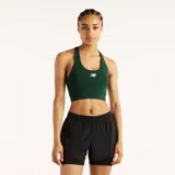 Top deportivo New Balance verde oscuro, con diseño de espalda cruzada y logo de la marca estampado en blanco en el pecho.