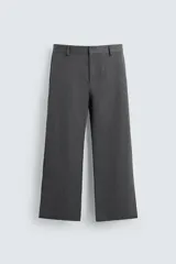 Pantalón de vestir gris oscuro, corte ancho (flare fit) y tiro alto, con bolsillos laterales y falsos bolsillos de vivo en la parte trasera. Presenta un cierre frontal con cremallera y gancho oculto, y botones a presión ocultos en el bajo.