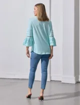 Blusa color celeste con escote en V, mangas largas acampanadas con detalle de crochet y frunces en los hombros.