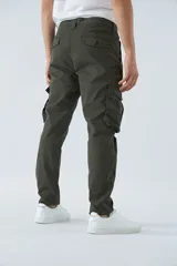 Pantalón cargo color beige, corte slim, con cierre y botón en la cintura, pasacintos, bolsillos cargo con botones y sin puños.