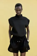 Bermuda color crema confeccionada en lino, de tiro alto con cintura elástica ajustable con cordones y bolsillos delanteros.