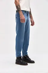 Jean de corte mom en color azul medio, con diseño de cinco bolsillos, cierre frontal con botón y bragueta, y costuras reforzadas.