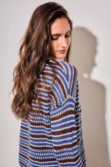 Sweater de punto con diseño de rayas horizontales en tonos ocre, marrón y crudo. Presenta cuello redondo, mangas largas y puños acanalados.