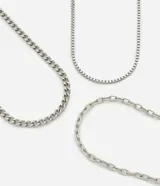 Kit de tres collares de metal plateado con diferentes tipos de cadenas: una cadena de eslabones gruesos y planos, una cadena de eslabones cuadrados (tipo caja) y una cadena de eslabones ovalados más finos.