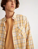 Camisa de manga larga a cuadros amarillos, blancos y grises, con bolsillo en el pecho y botones de pasta.