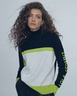 Sweater de tejido fino con diseño color block en negro, blanco y verde lima. Presenta cuello alto tipo polera, mangas largas con detalle de texto estampado en contraste y corte recto.
