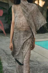 Falda pantalón de tiro bajo con estampado de puntos negros sobre fondo beige. Presenta un diseño de superposición con cierre lateral mediante lazadas y cremallera oculta, finalizando en bordes con detalle de franja negra.