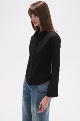 Camisa de algodón negra, de corte entallado, con cuello clásico y cierre frontal de botones.