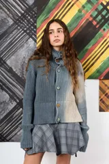 Saco de hilo con cuello alto y cierre de botones, de tejido de punto y diseño oversize. Presenta un teñido artesanal degradado que combina gris y beige, con mangas largas y puños amplios, además de un detalle de aplicación floral oscura en el pecho.
