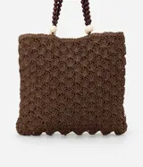 Bolso de mano tipo tote, tejido en punto de ganchillo con textura de conchas, color marrón oscuro. Las asas son de cuero o material sintético oscuro, adornadas con cuentas redondas de madera en tonos marrón oscuro, borgoña y crema.