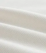 Bata masculina de manga larga en color blanco, confeccionada en tejido texturizado de algodón y poliéster. Presenta cuello en V con detalle de cordones cruzados y lazo ajustable.