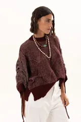 Buzo de punto color vino con diseño de trama geométrica, cuello redondo, mangas largas con puños ajustables mediante cordones y terminaciones acanaladas.