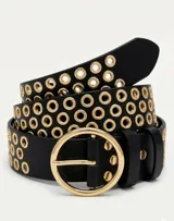 Cinto negro de cuero sintético con triple hilera de ojales metálicos dorados y hebilla circular grande de metal dorado.