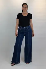 Pantalón wide leg de jean azul oscuro con costuras frontales marcadas y aberturas en los bajos.