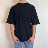 Remera negra de corte oversize con estampado gráfico en la espalda que presenta hongos en tonos violeta y verde, junto con la frase 'Curbside Treasures' y texto descriptivo.