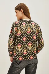 Sweater de punto con cuello redondo y manga larga, estampado en tonos oscuros con motivos geométricos y florales en rosa, amarillo y verde.