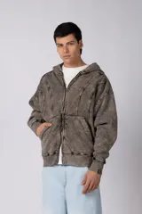 Campera oversize con capucha y cierre frontal, confeccionada en tela con acabado acid wash que le otorga un aspecto desgastado. Presenta costuras curvas decorativas en el frente y la espalda, puños y ruedo acanalados, y un calce relajado.