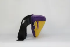 Riñonera de nylon con diseño bicolor en amarillo y violeta, con el logo oficial de Los Angeles Lakers estampado en el frente. Cuenta con cierre principal y correa regulable.