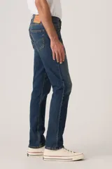 Jeans de corte slim fit en denim azul con lavado clásico, diseño de cinco bolsillos y cierre frontal con botones.