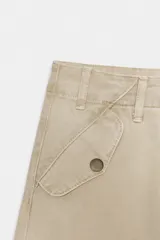 Pantalón cargo de tiro medio confeccionado en algodón, con diseño de pierna ancha, cintura con trabillas, bolsillos delanteros y bolsillos de plastrón con solapa en la pierna.