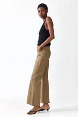 Pantalón tobillero de corte bootcut en lona de algodón, color marrón, con cintura estándar, bolsillos delanteros y pliegues marcados.