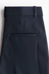 Pantalón cigarette azul marino de tejido elástico, con cintura estándar, bolsillos al bies y perneras ajustadas con raya marcada.