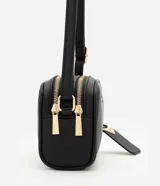 Cartera pequeña de hombro marca Satinato, confeccionada en PU con textura granulada. Presenta doble compartimento con cierre de cremallera metálica dorada, correa larga ajustable y un dije decorativo metálico con el logo de la marca.